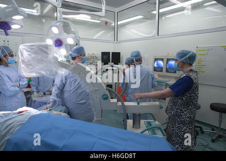 Medical staff in a hospital operating theatre during an operation checking the patients' X Ray on the screen Stock Photo