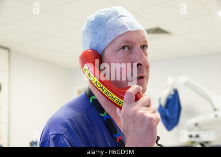 A doctor in a hospital ward uses the emergency telephone to ring for assistance Stock Photo