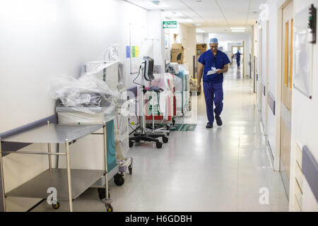 A surgeon walks along an NHS hospital corridor wearing scrubs Stock Photo