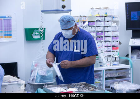 A nurse in scrubs opens sterile packages in a hospital operating theatre during an operation Stock Photo