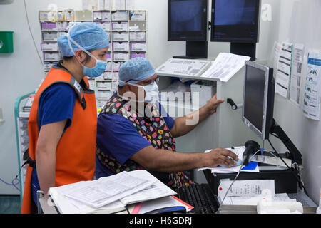 Two theatre technicians checks the patients' data on the screen during an operation Stock Photo