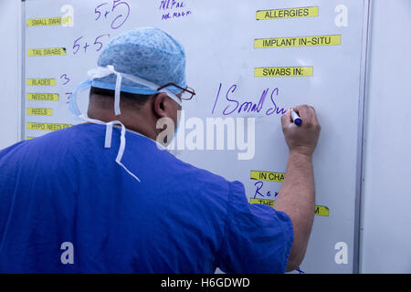 A theatre technician records the instruments and items used during an operation on a board in the operating theatre Stock Photo