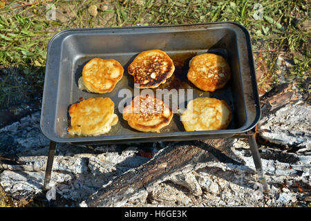 Cooking on the campfire pancakes for Breakfast. The pan with the tortillas on the fire. Stock Photo