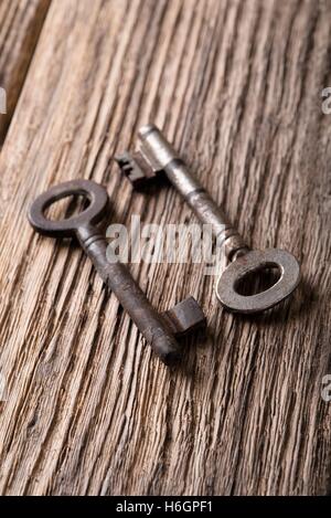 Vertical photo. Two old keys. Old keys placed on wooden board. Wooden board with worn surface. Dark photos. Board from planks. K Stock Photo