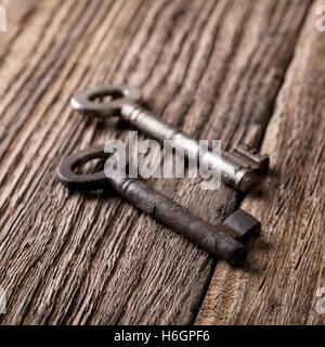 Square photo. Two old keys. Old keys placed on wooden board. Wooden board with worn surface. Dark photos. Board from planks. Key Stock Photo