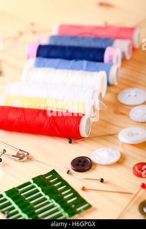 Vertical photo with several sewing accessories as buttons, measuring tape, threads or pins. Detail is on several colorful thread Stock Photo