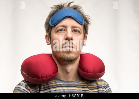 Bearded man with sleeping mask, red travel pillow on white background closeup Stock Photo