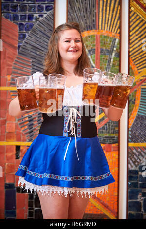 Waitress holding six beer steins during an Oktoberfest event Stock Photo