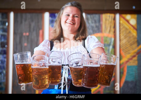 Waitress holding six beer steins during an Oktoberfest event Stock Photo