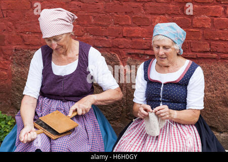 Two ladies dressed in traditional costume carding and knitting, Den Gamle By, Aarhus, Denmark Stock Photo