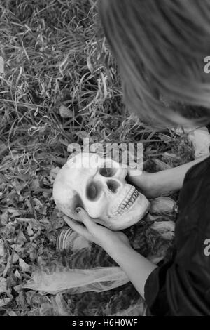 black and white picture of child alone in forest holding skull Stock Photo