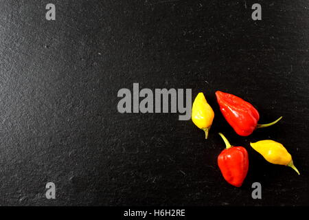 red and yellow ghost chili peppers on a slate plate Stock Photo
