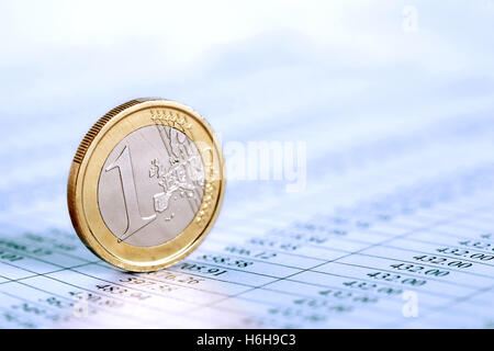 One Euro coin standing on paper background with digits table Stock Photo