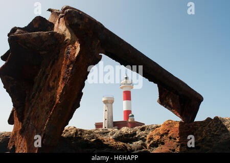 Fuerteventura, Canary Islands: El Toston Lighthouse, whose original structure was opened in 1897, seen through the rusty scrap of the wreck of a ship Stock Photo