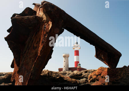 Fuerteventura, Canary Islands: El Toston Lighthouse, whose original structure was opened in 1897, seen through the rusty scrap of the wreck of a ship Stock Photo