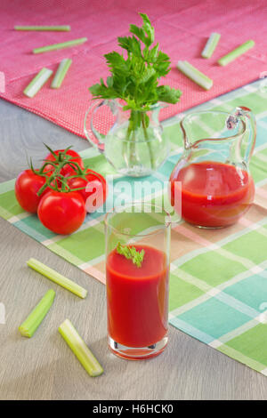 Glass with tomato juice, tomatoes, stalks and leaves of a celery on table Stock Photo