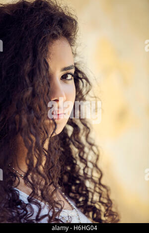 Young woman with curly hair covering eye with hand against wall Stock Photo  - Alamy