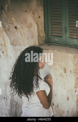 Sad young woman leaning against the wall outdoors Stock Photo