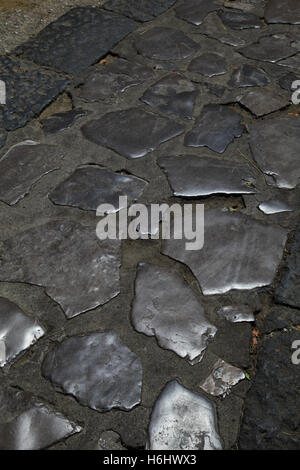 Stone set footpath footway polished with use over many years trafficked to a high shine buffed glossed glossy reflective tactile Stock Photo