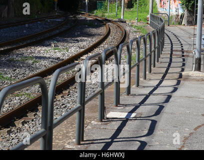 rail lines hoops barriers shadows linked rusty platform safety passengers cables poles electricity edge of platform gap doors. Stock Photo