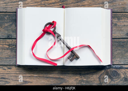 key tied with a red ribbon on a blank book Stock Photo