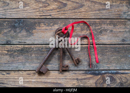 three keys tied with a red ribbon on wooden background Stock Photo