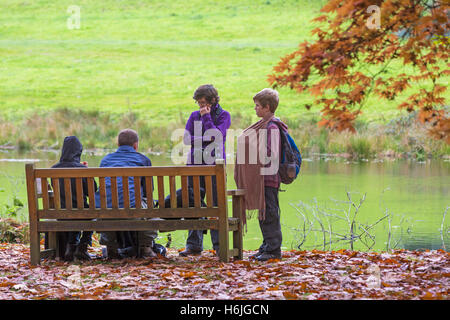 Family on bench by river with Autumn leaves in October Stock Photo