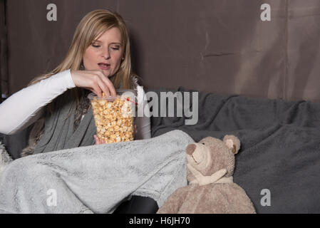 Attractive woman with teddy eating popcorn from bucket Stock Photo