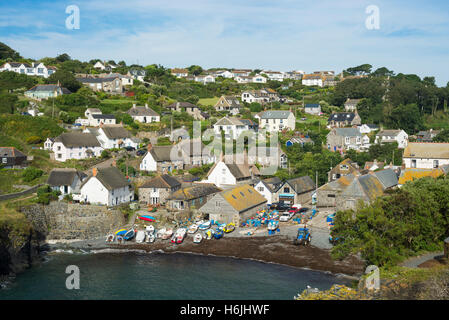 Cliffs, pebbeld beach, fishing boats and thatched roof cottages of the picturesque Cornish coastal village of Cadgwith shine in the morning sun Stock Photo