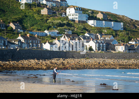 Fisherman on the beach of Sennen Cove in front of the houses of the coastal town Sennen in the morning sun, Cornwall,England,UK Stock Photo