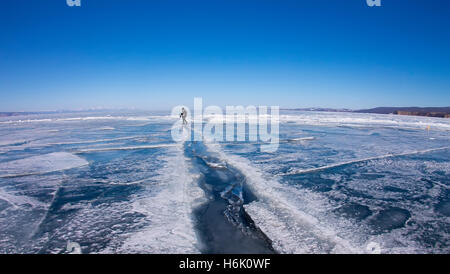 Man goes through a large crack in the ice of Lake Baikal. Stock Photo