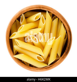 Penne rigate pasta in wooden bowl. Uncooked dried durum wheat semolina noodles. Short-cut medium length tubes with ridges. Stock Photo