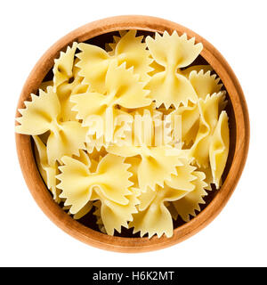 Farfalle pasta in wooden bowl. Uncooked dried durum wheat semolina pasta. Decorative short-cut bow tie or butterfly shaped. Stock Photo