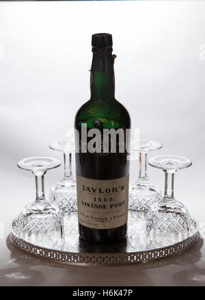 A bottle of Taylors 1966 vintage port, with four crystal glasses on a silver tray. Stock Photo