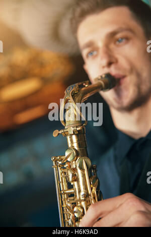 Young man in suit playing on saxophone Stock Photo