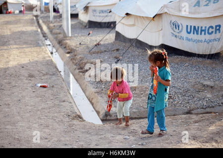 A boy and a girl run down a gravel path between refugee accommodations in the Debaga refugee camp between Mosul and Erbil, Iraq, 18 October 2016. The UN refugee aid organisation expects up to a million refugees from the fighting for Mosul. Germany will be making 34 million euros in immediate aid available in the region. According to UNICEF, more than 500,000 children and their families will be great danger over the next few weeks due to the recapturing of the city of Mosul. In anticipation of a wave of refugees, materials, especially for the water supply, are being brought into the region. Pho Stock Photo