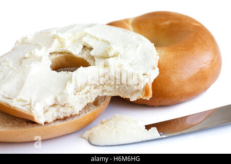 Plain bagel with knife, spread with cream cheese and bite missing. Stock Photo
