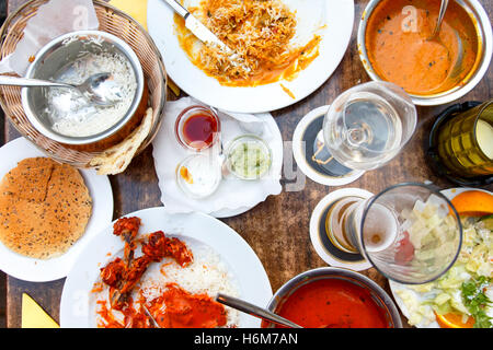 Plates of Indian food leftovers on wooden table from above. Stock Photo