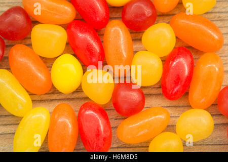 Colorful jelly beans of different sizes close to wallpaper Stock Photo