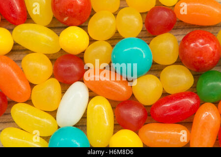 Colorful jelly beans of different sizes close to wallpaper Stock Photo