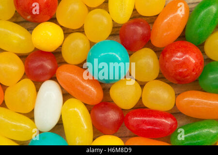 Colorful jelly beans of different sizes close to wallpaper Stock Photo