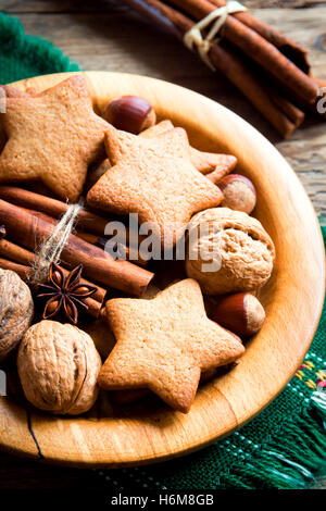 Rustic Christmas decoration with gingerbread cookies, nuts and Christmas spices on wooden plate close up Stock Photo