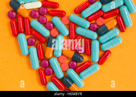 Heart medicine. Pills arranged in heart shape on an orange background Stock Photo
