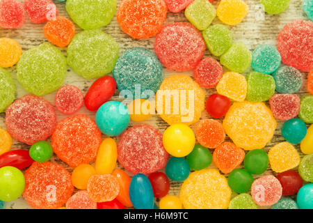 Colorful jelly beans of different sizes close to wallpaper Stock Photo