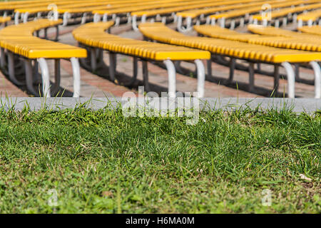 neat rows of green benches on a background of green grass Stock Photo