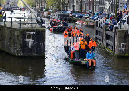 People in boats celebrating King's Day on the canals and by the river banks in Amsterdam, Netherlands. Stock Photo