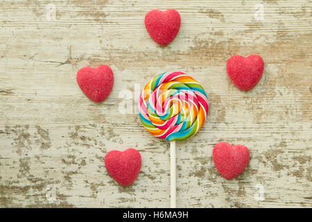 Jelly beans hearts with a colorful lollipop on a wooden background Stock Photo