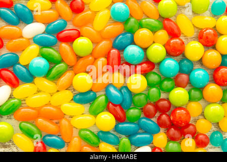 Colorful jelly beans of different sizes close to wallpaper Stock Photo