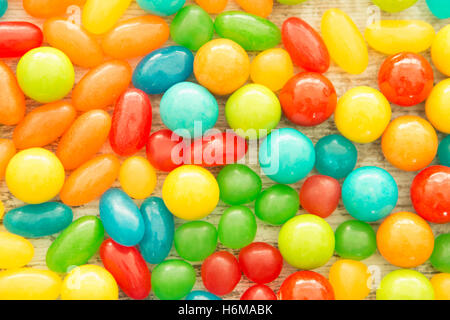 Colorful jelly beans of different sizes close to wallpaper Stock Photo