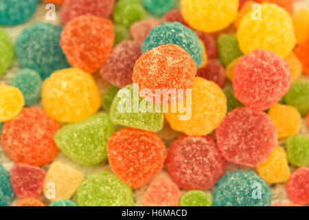 Colorful jelly beans of different sizes close to wallpaper Stock Photo